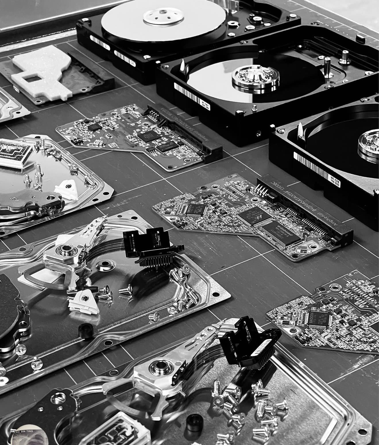 Disassembled hard drives laid out and indexed on a cutting mat