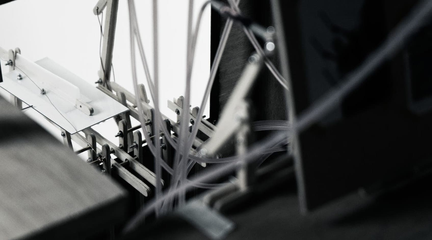 Close-up through the model — plastic tubing crossing the wooden linkages of the parasite mechanisms