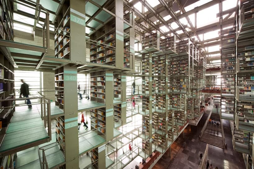 Reference interior — figures crossing glass-floored walkways between hanging book stacks