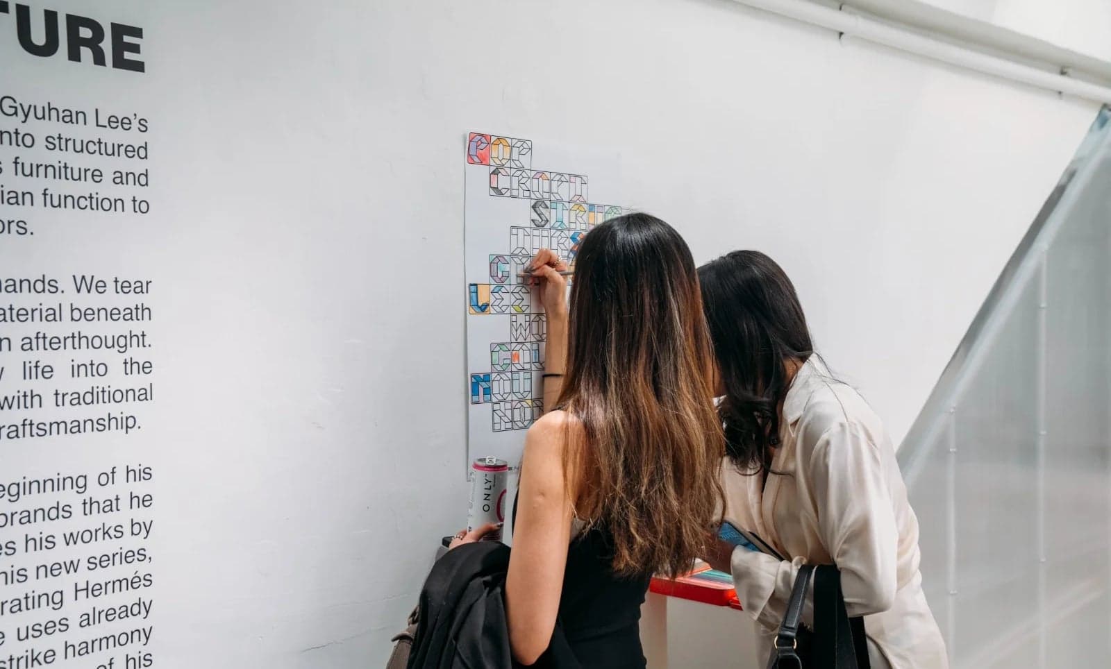 Visitors colouring the letterform poster on the gallery wall during an opening
